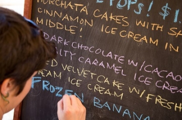 someone writing on a cafe menu board