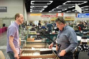 man talking to a dealer at a coin show booth