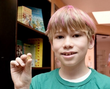 young boy holding a small coin