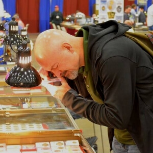 man bent over booth at coin show